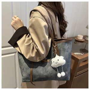 Detail of large grey tote bag with contrast brown trim and cute cloud charm on shoulder