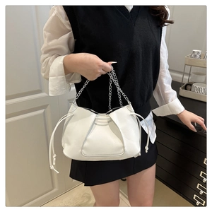 Detail of white pleated mini bucket bag with silver chain strap and drawstring closure