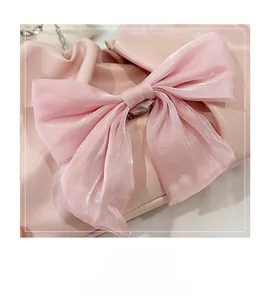 Détail macro d'un grand nœud en organza rose et de similicuir souple sur un sac à main femme