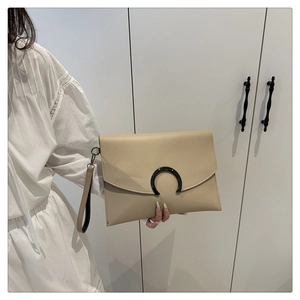 Close-up of beige envelope clutch bag featuring black C-shaped buckle and wrist strap