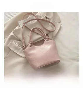 Close-up of pink bucket bag with embossed cartoon rabbit patterns and round handles