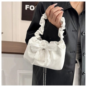 Detail of white handbag with large bow, ruched handle and fine metal chain detail