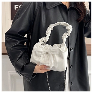 Détail du sac plissé blanc avec grand nœud en tulle et bandoulière chaîne argentée