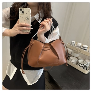 Detail of caramel brown PU leather bag with drawstring closure and silver chain strap