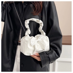 Detail of white satin bow handbag with pleated handle and elegant metal chain strap