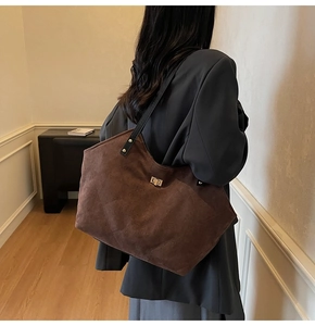 Détail du sac cabas en daim marron avec motif matelassé en losange et fermoir rotatif doré