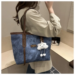 Detail of denim tote bag with brown leather trim and cute white cloud charm