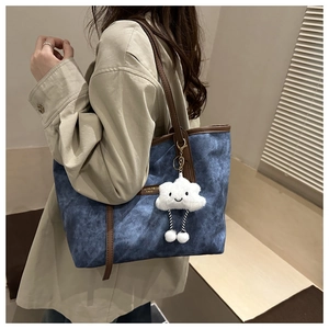 Detail of blue denim tote bag with brown leather trim and cute white cloud charm