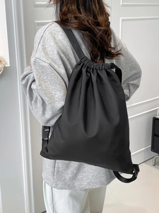 Minimalist black nylon drawstring backpack for travel shown on model back view