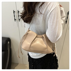 Beige pleated leather crossbody bag with silver chain strap shown on model's shoulder