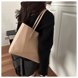Close-up of geometric leather paneling and gold brand logo on beige shoulder bag