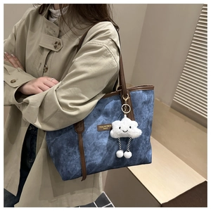 Detail of denim blue tote bag with brown leather handles and cute cloud plush pendant