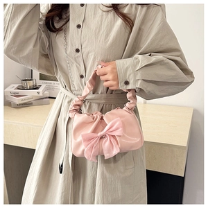 Détail du sac bandoulière en satin rose clair avec grand nœud et poignée plissée