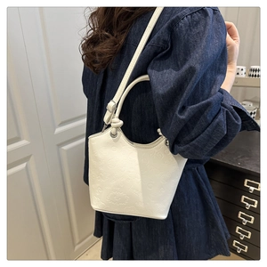 Detailed close-up of white bucket bag featuring cartoon embossed textures and handle