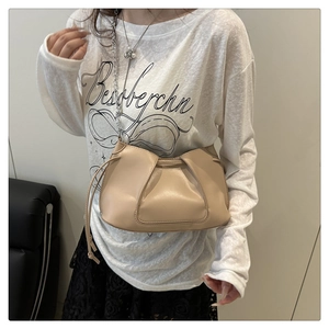 Detail of beige pleated cloud bag with soft leather texture and slim shoulder strap