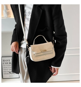 Detail of minimalist cream leather handbag with gold metal clasp and top handle
