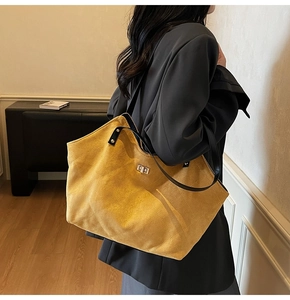 Detail of a large yellow quilted tote bag with silver metal twist lock and suede texture