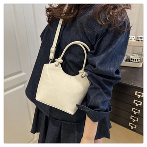 Detail of cream white handbag with cartoon embossed pattern and thin shoulder strap