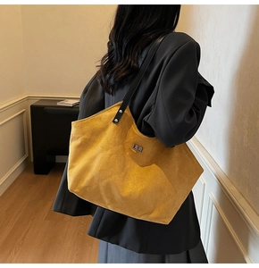 Détail du sac cabas en daim matelassé jaune avec fermoir métallique et bandoulière noire