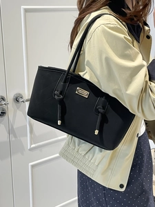 Black quilted tote bag with gold hardware and crocodile texture shown on a female model