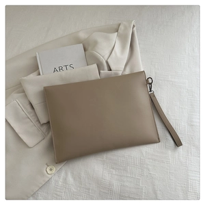 Detail of the khaki leather envelope clutch showing the sleek texture and wrist strap