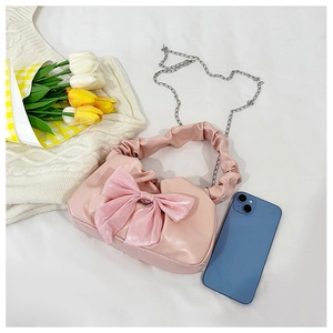 Détail d'un sac à main rose style doux avec un grand nœud et une poignée à volants