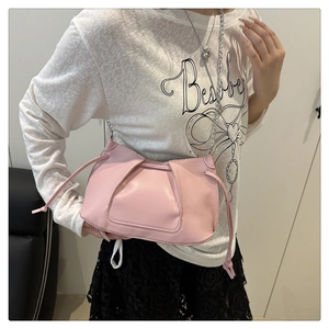 Detalle de bolso bandolera rosa plisado con cadena plateada sobre conjunto blanco
