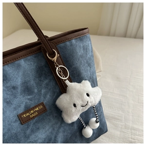 Detail of blue denim tote bag with brown leather trim and cute white plush cloud charm