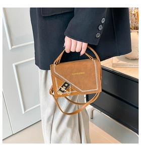 Detail of vintage brown crossbody bag with contrast stitching and metal lock on leather