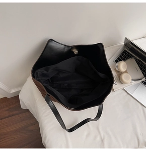 Vue de dessus d'un grand cabas en cuir marron et noir montrant l'intérieur spacieux et pratique