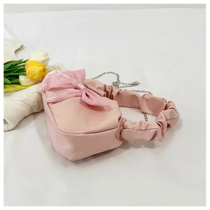 Détail du sac à main rose avec nœud en tulle, poignée froncée et bandoulière chaîne