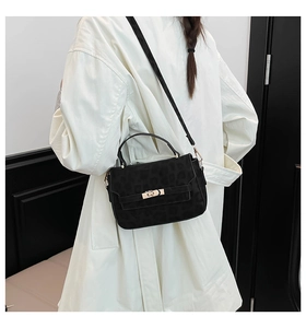 Détail du sac léopard noir avec fermoir doré porté sur un manteau blanc chic
