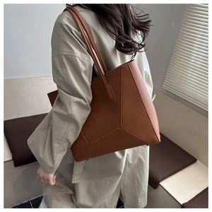 Detailed side view of a brown leather tote bag with decorative stitching and long straps