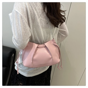 Pink pleated tote bag with silver chain strap shown as a crossbody on a female model