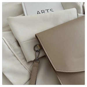 Detail view of tan envelope clutch with fine stitching and gunmetal hardware accents