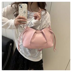 Detalle de bolso rosa con diseño plisado, cordón lateral y correa de cadena plateada