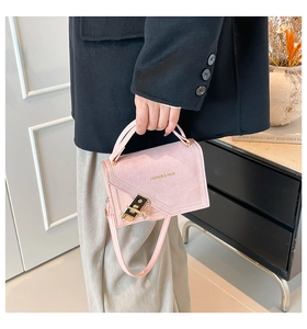 Detail of pink faux suede handbag with gold hardware and stylish metal lock closure
