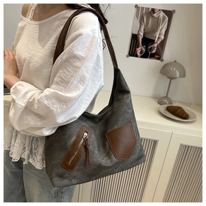 Detail of large dark grey canvas handbag with brown leather trim and zipper tassel
