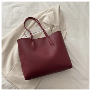 Detail shot of a burgundy leather tote bag featuring silver protective bottom feet