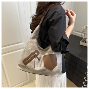 Detail of vintage gray canvas shoulder bag with brown leather trim shown on model