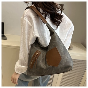 Close-up of dark grey canvas tote with brown leather straps and zip pocket on model