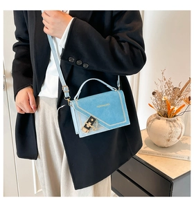 Detail of light blue square crossbody bag with gold fashion text and chain strap