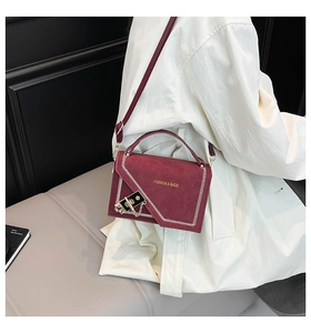 Detail of burgundy frosted shoulder bag with white V-stitching and chain on model