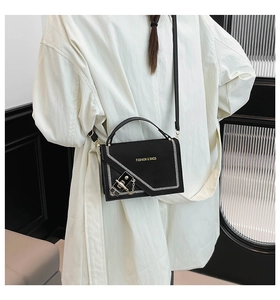 Detail of black crossbody bag featuring white wavy stitching and a gold metallic buckle