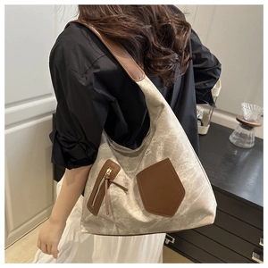 Back view of a large canvas tote bag with brown leather straps and pocket on a model