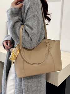 Sac cabas en cuir beige avec surpiqûres blanches et foulard fleuri, porté par un mannequin