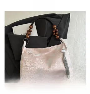Detail of pink Chinese silk handbag with pine crane embroidery and wooden bead handle