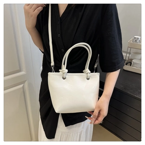Detailed close-up of white crossbody bucket bag with knot handle and shoulder strap