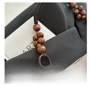 Detail of woven rope handle with natural wood beads and floral jacquard satin fabric