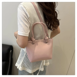 Gros plan du sac à bandoulière rose porté par un mannequin montrant la taille et le cuir